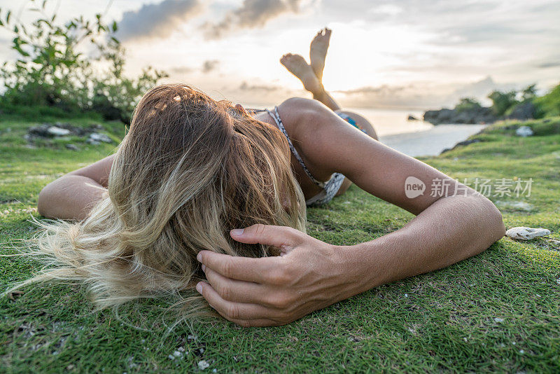 年轻女子在热带岛屿放松日落，性感
