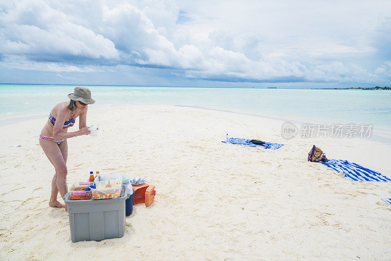 游客，在马尔代夫Maffushi岛附近的一个长长的沙滩上吃午饭的老妇人