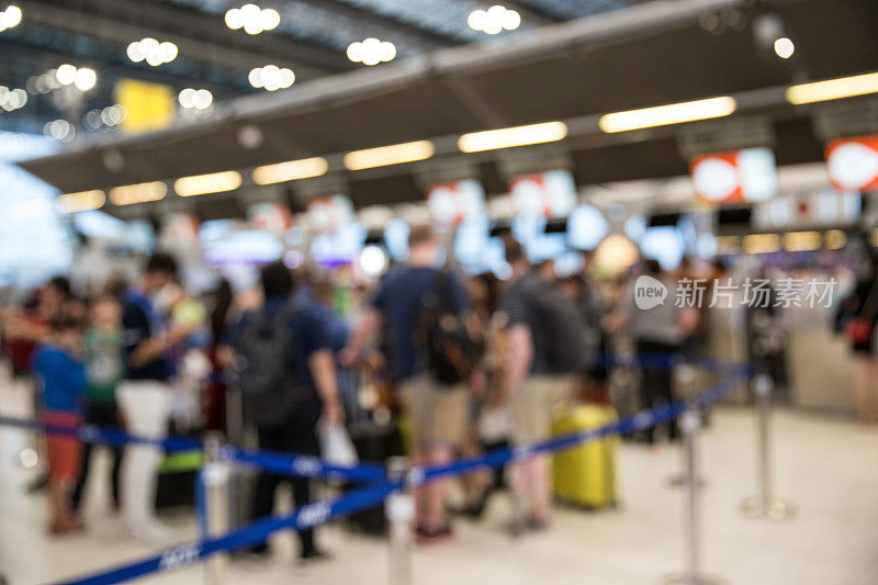 模糊的机场值机柜台上挤满了乘客。