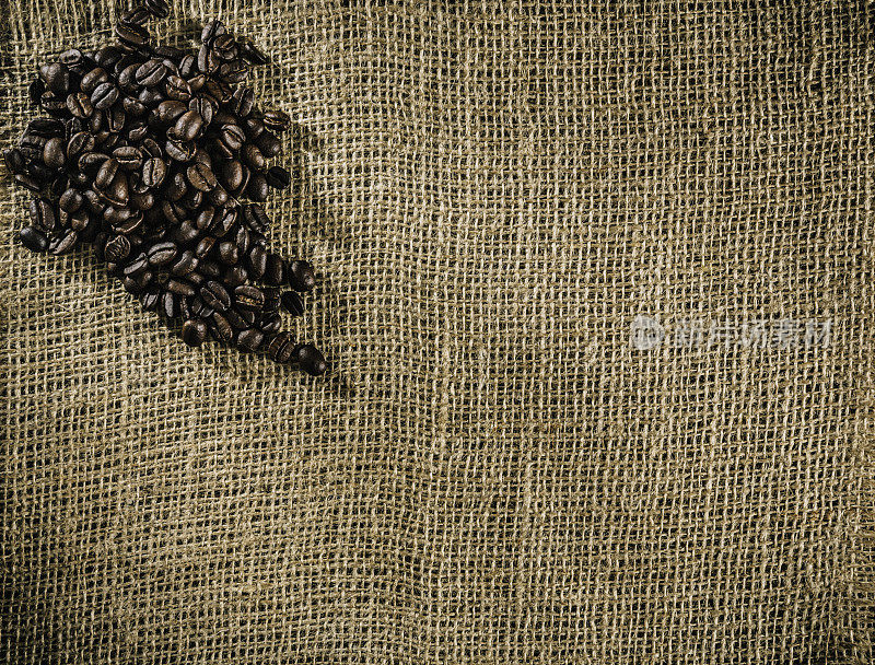 烤生咖啡豆在黄麻背景与拷贝空间