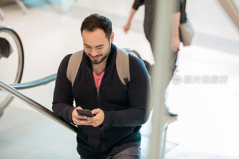 一名男子在登上机场自动扶梯时发短信