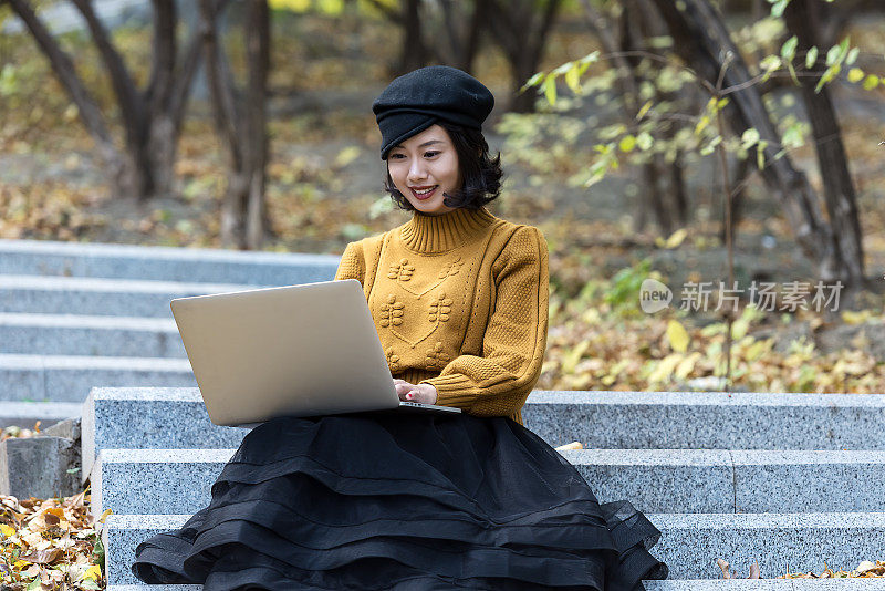 一个亚洲女孩在公园里操作笔记本电脑