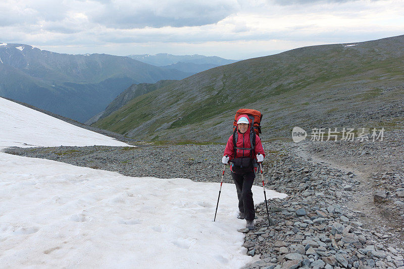 一名女游客在俄罗斯阿尔泰山卡拉塔瑞克山口的雪坡上爬山