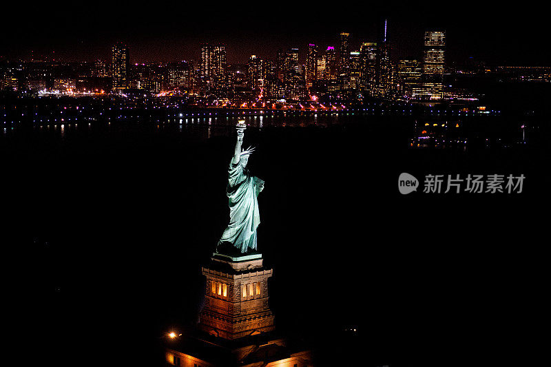 空中俯瞰自由女神像在纽约的夜晚，以曼哈顿市中心为背景