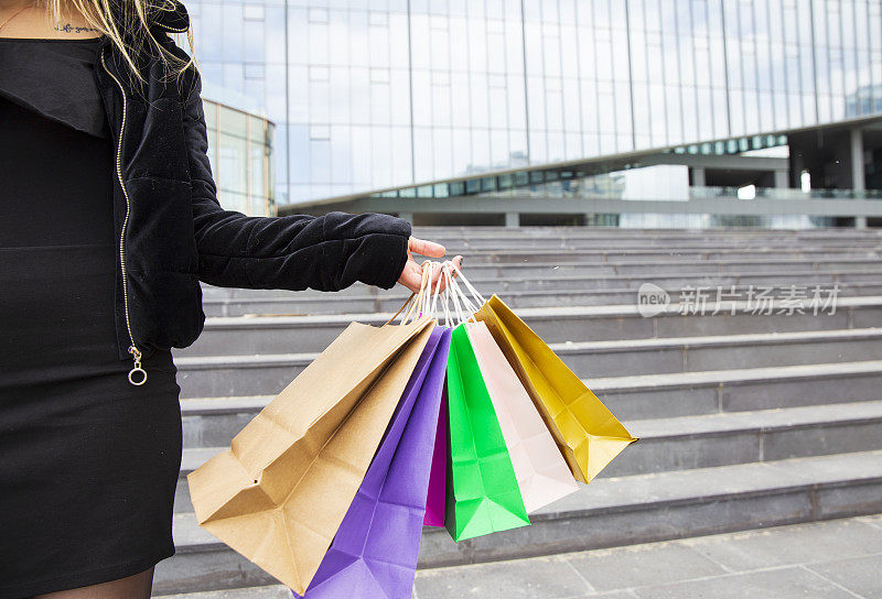 女人拿着许多购物袋在时尚精品店，闪光。消费主义和销售观念