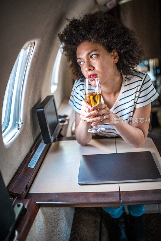 年轻的富婆坐着私人飞机，用长笛喝着香槟，看着窗外