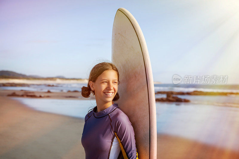 少女在海滩上微笑着学习冲浪板