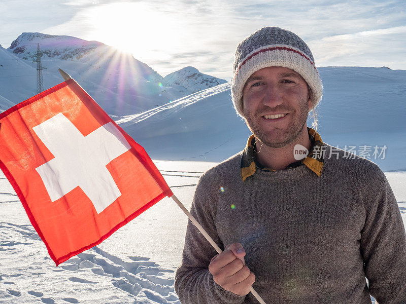 在瑞士阿尔卑斯山雪山上的男人的肖像拿着瑞士国旗