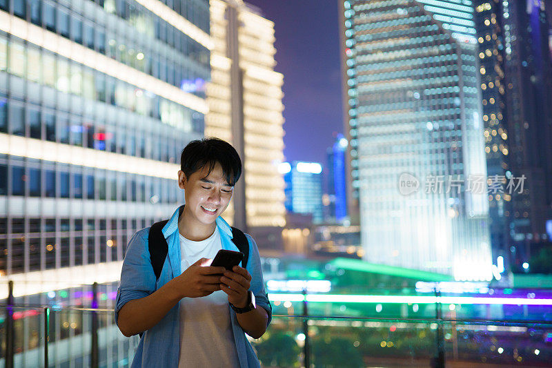 年轻的亚洲男子在晚上使用智能手机