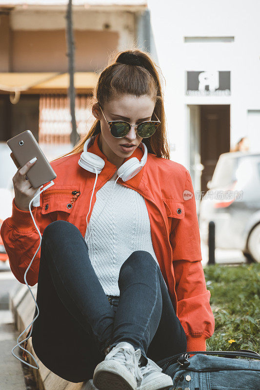 吃着冰淇淋的迷人女人正坐在户外，用智能手机输入信息