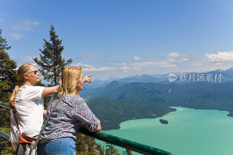 两个金发女人望着阿尔卑斯山和高山湖泊