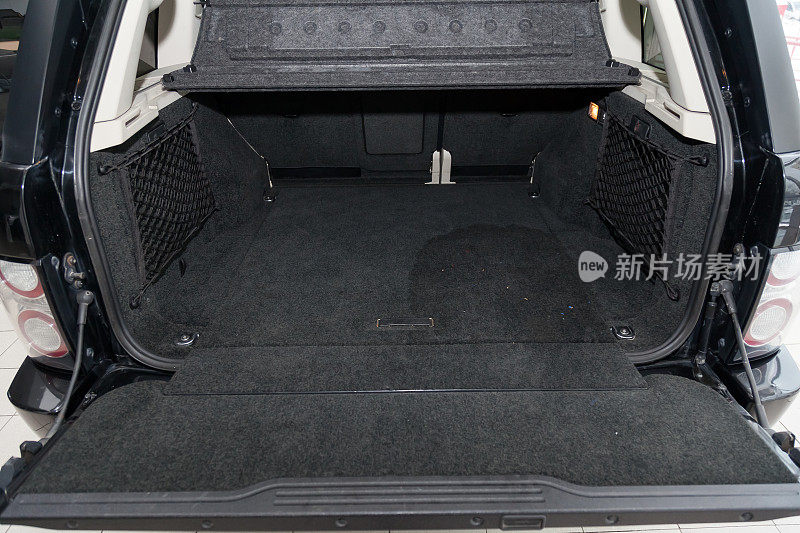 打开一辆越野车的空后备箱，在清洗和吸尘前，用一种特殊黑色材料的地毯地垫准备装入行李。汽车服务行业。