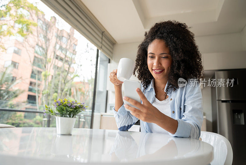 在家里一边喝咖啡一边玩智能手机的女人