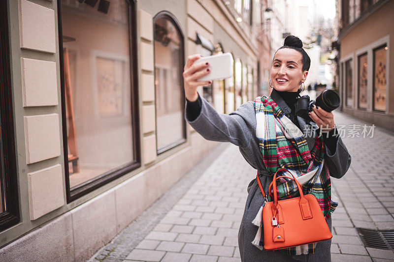 一位快乐的女性独自旅行者在城市照片之旅中自拍