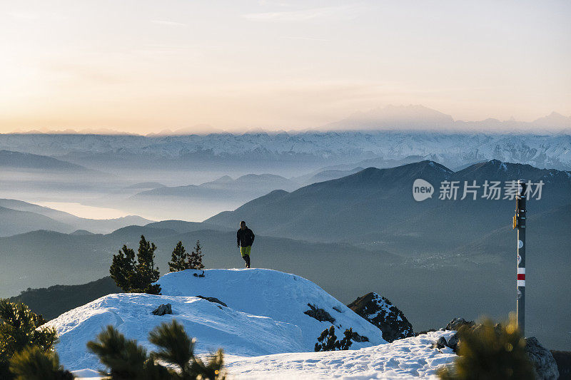 黎明时分，一名徒步运动员爬上雪山的山脊