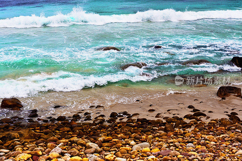 海浪拍打着水边，拍打着布满卵石的海岸