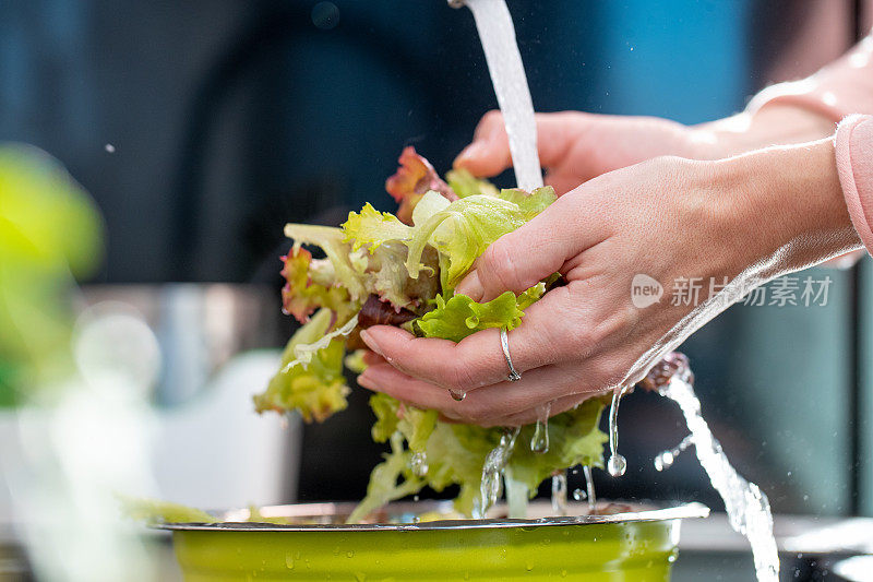 在水槽边的水龙头下洗生菜