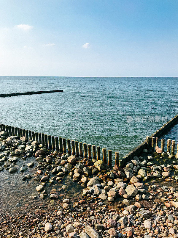 波罗的海海岸-岩石海滩与防波堤和蓝色的海对抗蓝天。