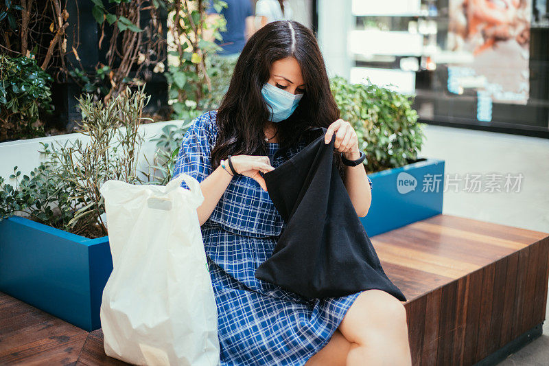 戴口罩的女人在钱包里找东西