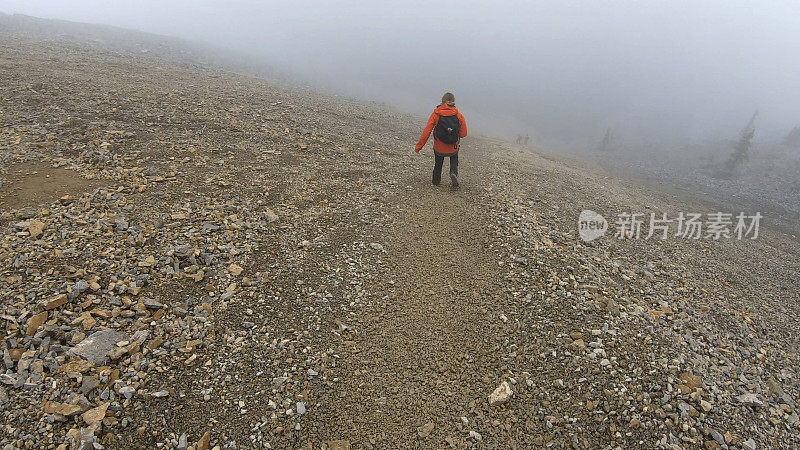 年轻的女登山运动员在雾中爬下一座山