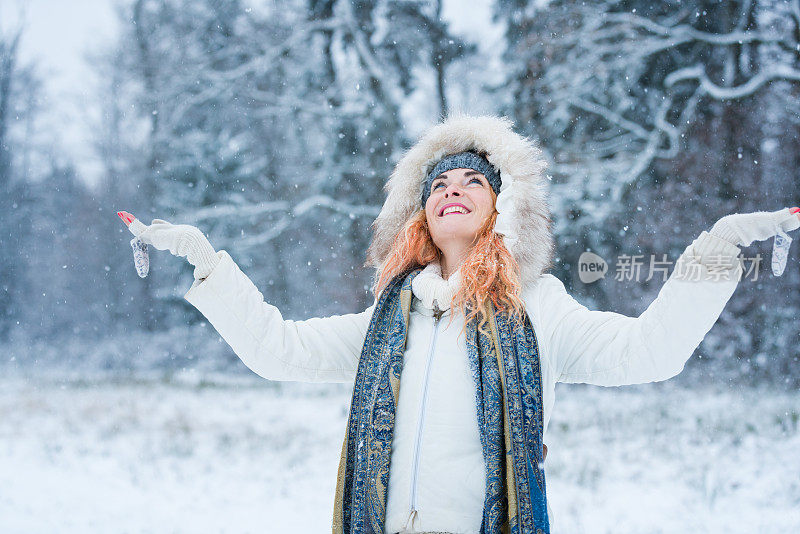 快乐的女人，在冬天森林附近的白雪皑皑的草地上