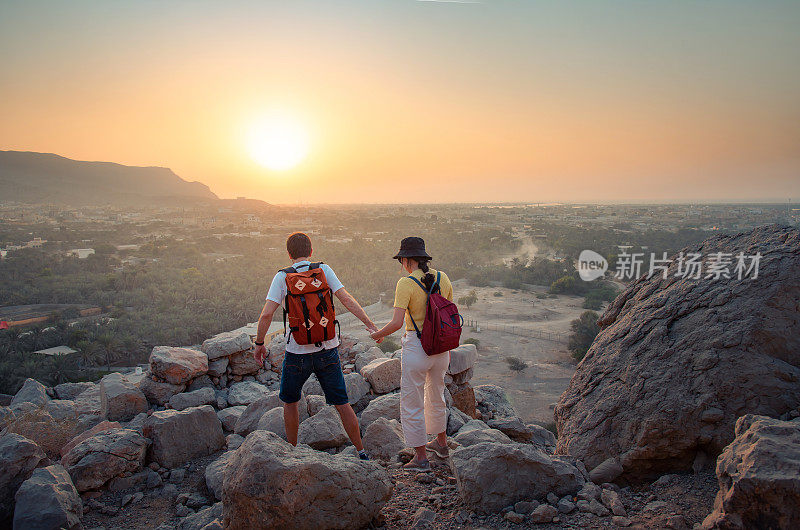 日落时分，一对夫妇爬上了阿联酋沙漠的山顶