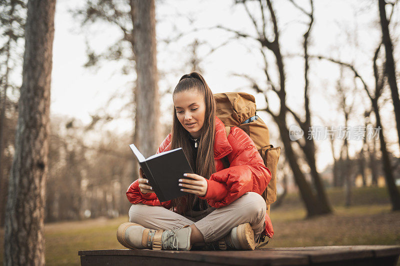 女人在山里徒步旅行时休息和阅读一本书