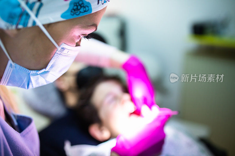 一名儿科女牙医正在检查一名小男孩的牙齿