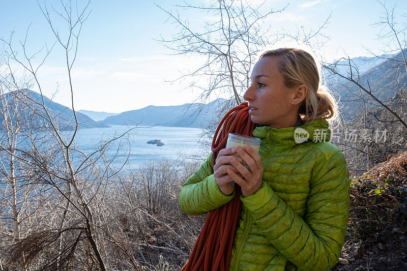 女性攀岩者用可重复使用的旅行杯喝水