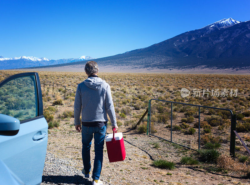 科罗拉多公路旅行:高级男子在车外与红色冷却器