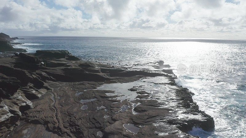 飞越火山峭壁。电影野生自然空中4K。透明的海水中缓慢运动的波浪。到美丽的夏威夷海滩进行户外探险旅行。阳光灿烂的夏日里，原封不动的大自然。