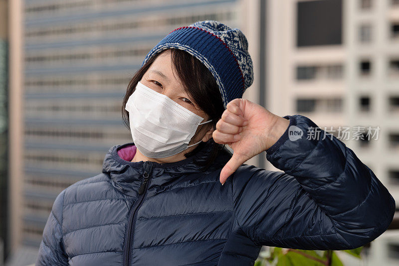 戴着口罩拇指朝下的女人