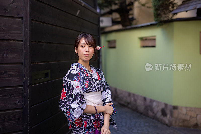 一位日本妇女站在一条狭窄的人行道上
