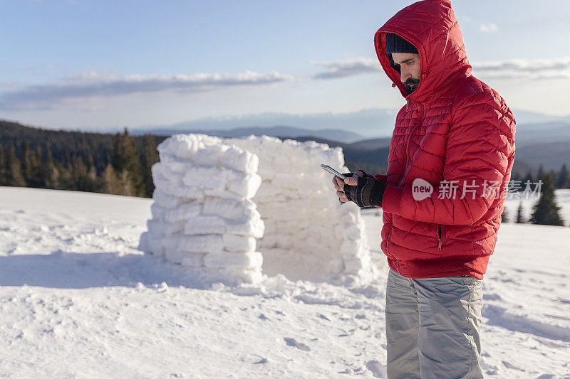 冬季登山露营时，在冰屋附近打电话的游客。在COVID-19大流行期间独自生活。心理健康和生活平衡。