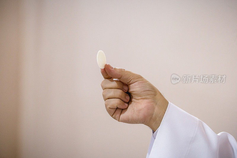 牧师的手拿薄饼，由受命牧师献祭的小面包，基督教和天主教的传统
