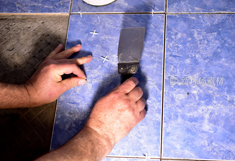 一个男人的手拿着抹刀在修理地板。