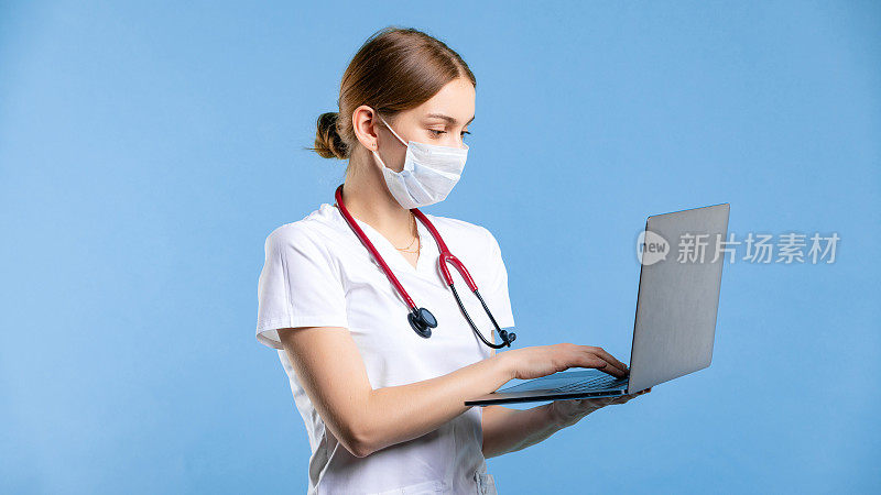 职业医生在工作室的女性肖像。为远程医疗使用笔记本电脑的妇女。孤立背景下的概念。妇女使用口罩进行冠状病毒卫生保健