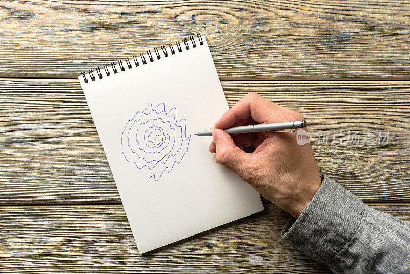 帕金森病患者手部震颤试验一个男人的手用钢笔在纸上画了一个螺旋特写。