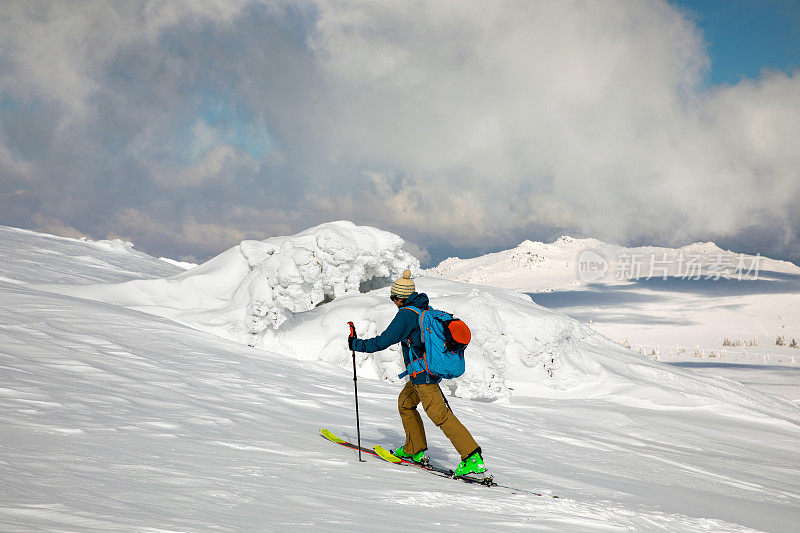 在美丽的冬日里远足的乡村滑雪者