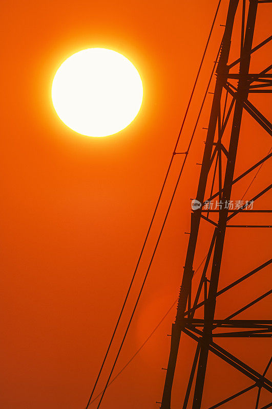 炎炎夏日，太阳落在高压输电塔后面