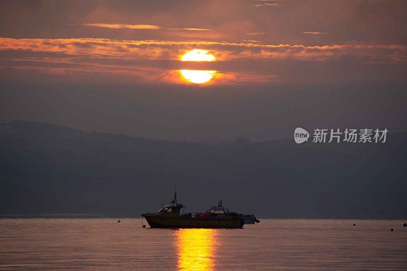 当船停泊过夜时，阳光反射在海面上。