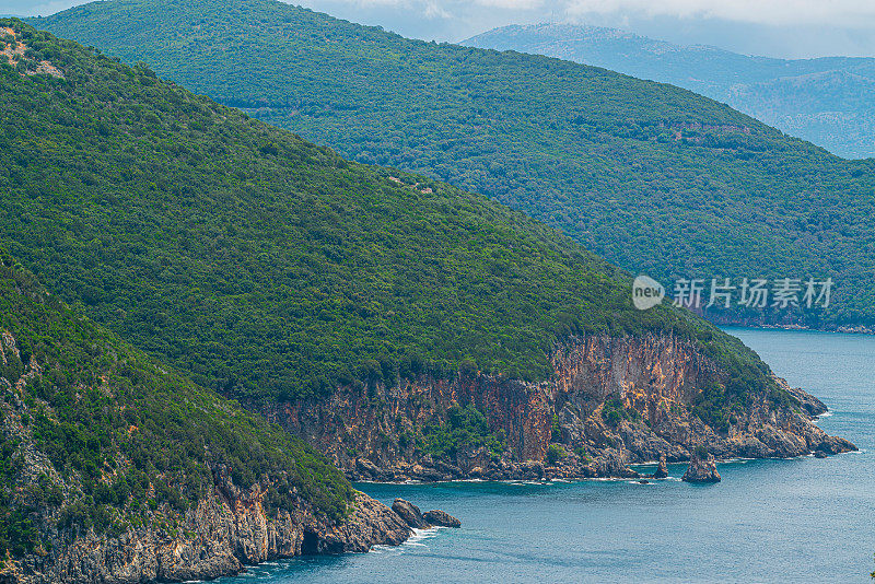 奇特的海滩附近的帕尔加与沙子和鹅卵石海滩和一个大岩石在蓝色的大海，在松树林。