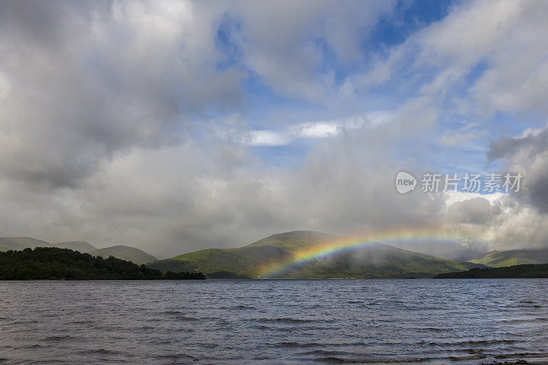 从英国苏格兰卡舍尔的海滩上看到的与洛蒙德湖接壤的山脉上异常低的彩虹弧线。