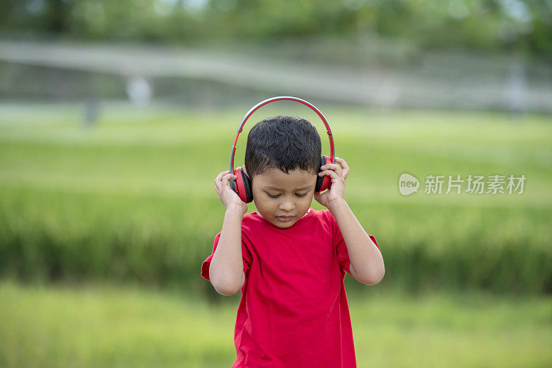 蹒跚学步的男孩用耳机听音乐