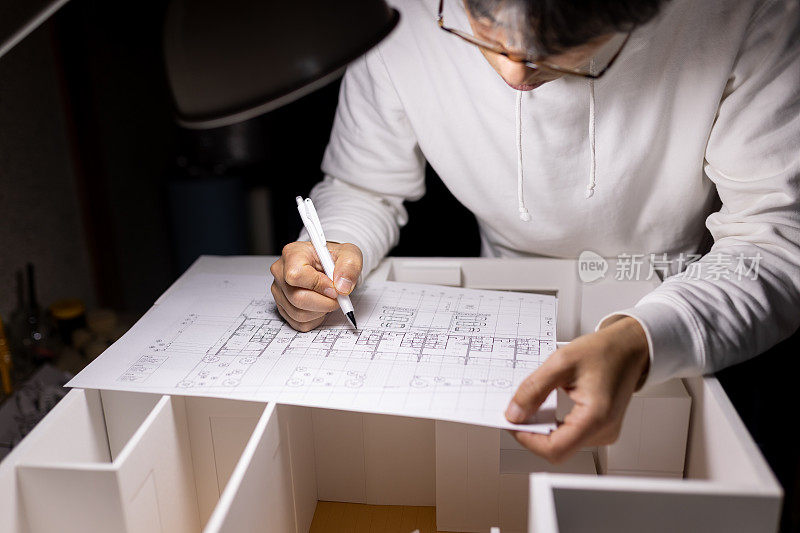 一位日本建筑师在家庭办公室里用模型和蓝图设计房子