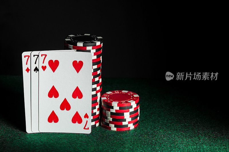 一种或一套组合有三张牌的扑克。在赌场打牌的特写和绿色桌子上的筹码。广告或刻字的空余空间