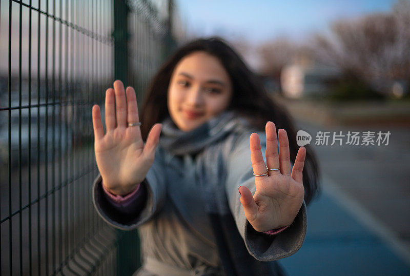 年轻的黑发女孩的肖像。
年轻女孩在看镜头时举手。