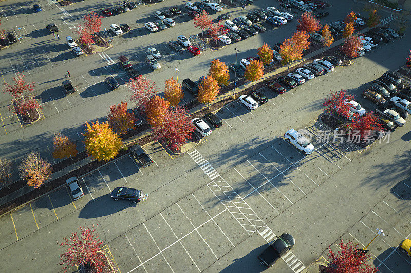 俯视图，许多汽车停在停车场前的条形购物中心广场。消费主义与市场经济的概念