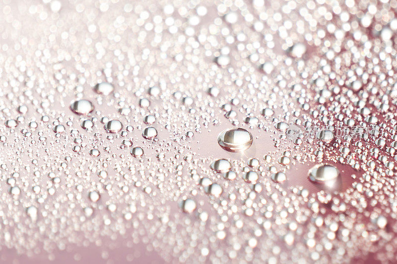 抽象化妆品的背景一滴润肤液在一个粉红色的背景。润肤水、化妆水、精华液。