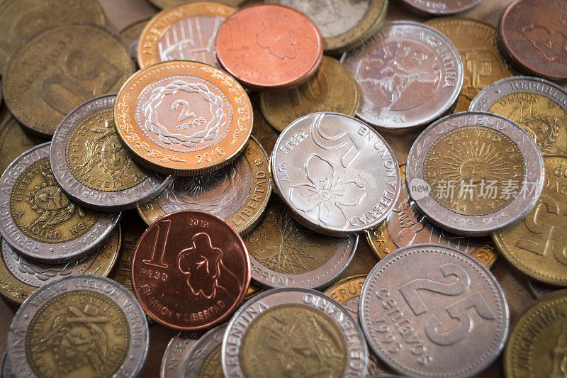 阿根廷比索硬币堆积在一起。闪闪发亮的硬币